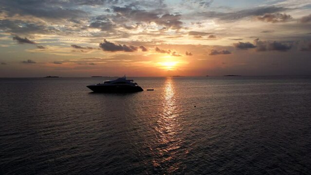 Aerial view of a modern live aboard dive ship moored at sunset in Dhangethi Lagoon with a sea plane passing. Maldives, Indian Ocean.