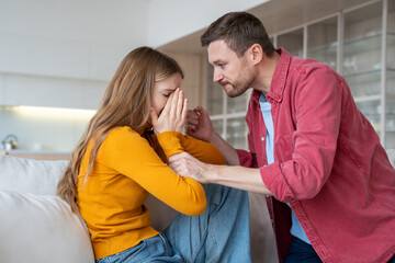 Despotical husband ready to hit, beat terrified helpless wife. Crying woman suffering from domestic violence. Relationship difficulties, gaslighting, conflicts, scandal, marital discord in family life - obrazy, fototapety, plakaty