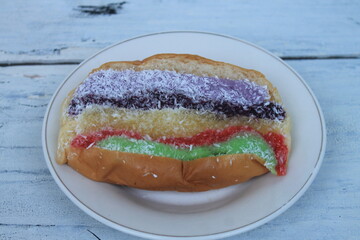 Torn bread topped with colorful jam and a sprinkling of grated coconut in a plate on the table
