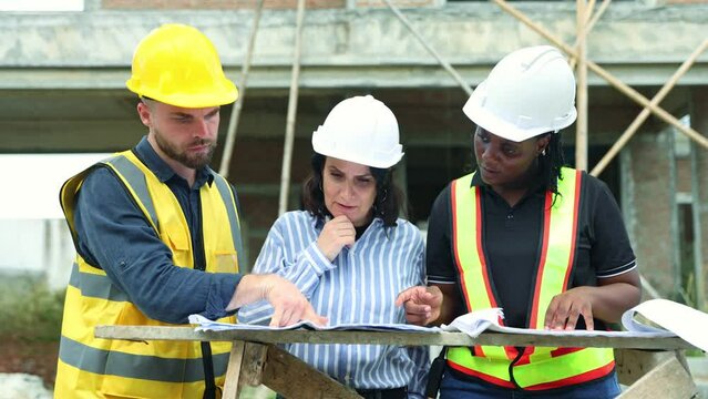 Meeting brainstorm house construction team architects engineers men and women and workers looking at blueprints consulting planning work housing projects real estate with civil engineers.