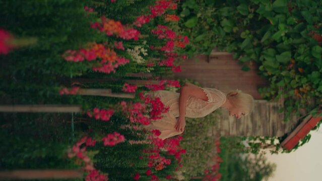 A young blond woman in a white lace dress running in the beautiful colorful flower field