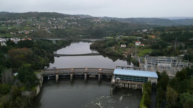 High angle aerial overview of power plant and dam with bridge reflection in water