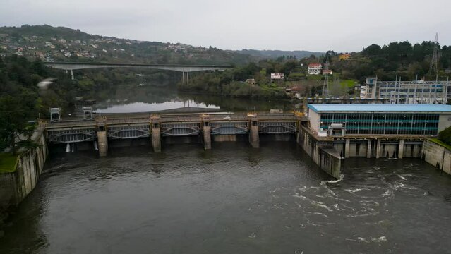Slow pan across water dam as birds soar in front of Velle water dam and power plant in Ourense, Galicia, Spain