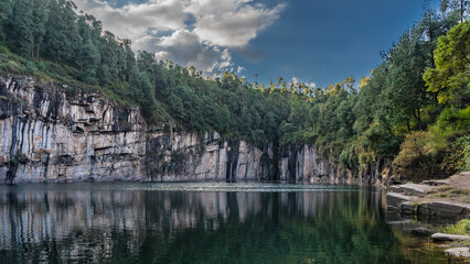 A beautiful lake in the crater of an extinct volcano. Coniferous forest grows on steep rocky...