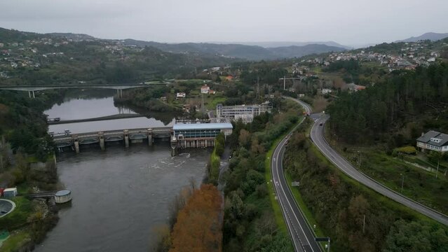 Flyover above highway road lining river by Velle water dam and power plant in Ourense, Galicia, Spain