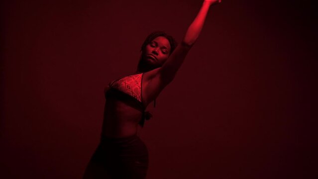 Studio shot of black woman dancing dancehall under neon lights