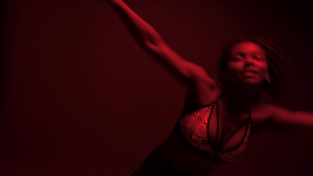  Black woman dancer with a vibrant expression performs dancehall under red lights