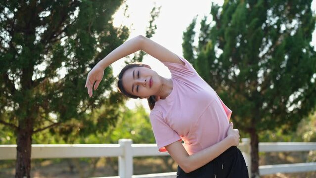 Image of health and healthy lifestyle of Asian woman in pink sportswear Preparing and stretching the muscles of the body and limbs for running in the park. Exercise outside the venue.