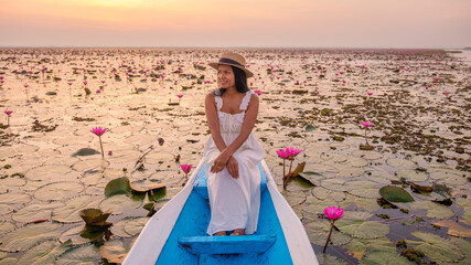 The sea of red lotus, Lake Nong Harn, Udon Thani, Thailand. Asian woman with a hat and dress on a...