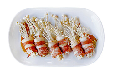 prepared bacon wrapped enoki mushroom or bacon rolls served on white plate dish isolated