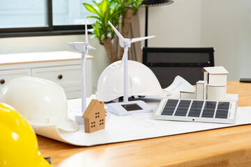 Wind turbines and solar cells A white and yellow engineer's hat sits on the table. Renewable energy...