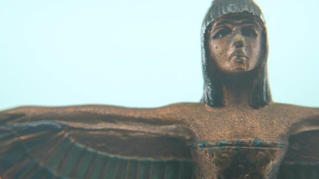 Dreamy macro shot of a Cleopatra statue with wide open wings, hazy depth of field, ancient Egypt Queen of Kings, Egyptian historical ruler, antique artwork of a goddess, smooth 4K video pan right