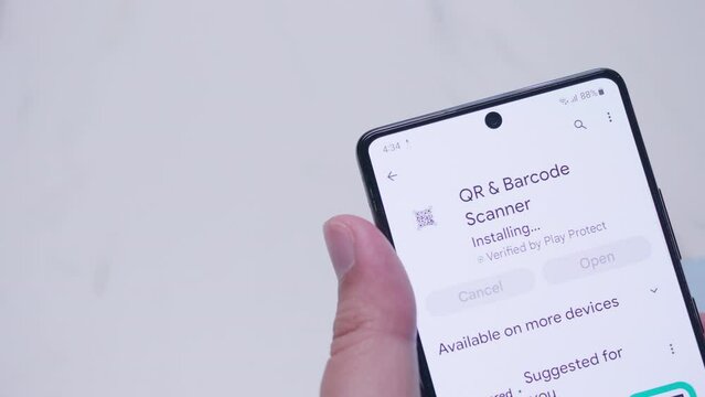 Close-up of an individual browsing the google play store to download and install a QR and barcode scanner.