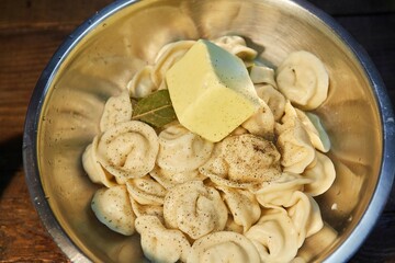 Ready-cooked dumplings in a bowl with spices and butter.