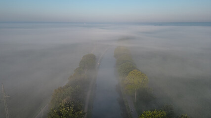 This serene image offers an aerial perspective of a country road cutting through a landscape...