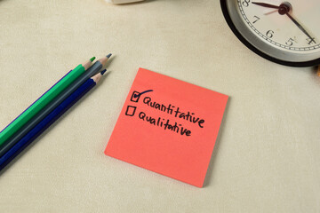 Concept of Quantitative or Qualitative write on sticky notes isolated on Wooden Table.