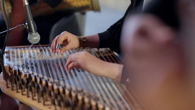 A woman playing on Zither in the theatre beside a man playing Oud high angle shot, close up