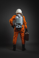 Fototapeta premium Astronaut is standing in the space suit and helmet on the gray background. Back view.