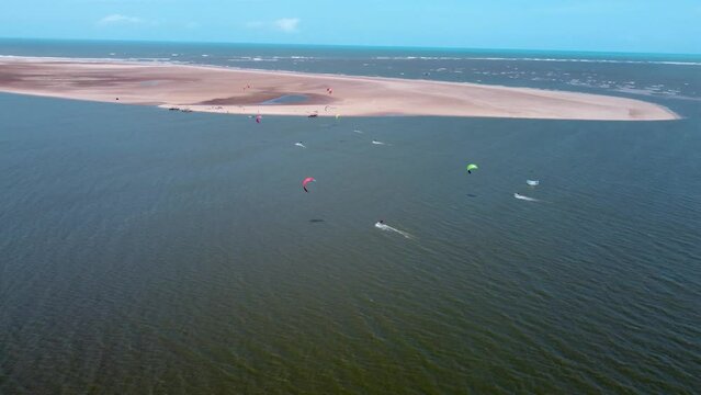 group of kiters riding next to a sand bank at the sea