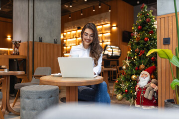 Young woman sitting in the restaurant and having a video call on laptop. Female professionals video calling on laptop sitting at cafe.