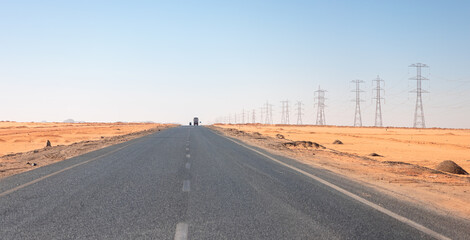 Asphalt road across the desert with Power line transmission towers surround the Sahara - Egypt