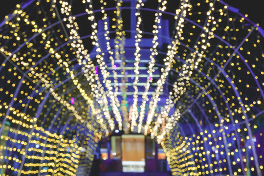 Blurred image bokeh background of Christmas decorative tunnel lights in front of entrance door of catholic church at night