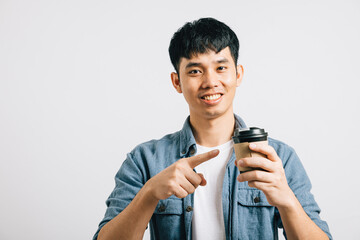 Portrait of a smiling Asian teenager with a takeaway coffee cup, pointing to his optimistic idea. Studio shot isolated on white background, radiating positivity.