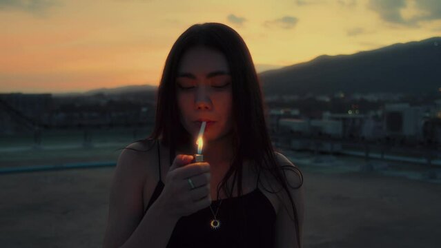 Young brunette woman smoking cigarette at rooftop with a mountain view