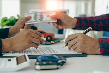 Car dealer hands keys to customer, closing car insurance documents or rental agreement or...