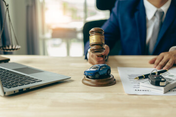 Lawyer, judge's gavel and miniature car as symbols of auction or court action against driver who got into an accident and received car insurance money on the table. Close-up view. - obrazy, fototapety, plakaty