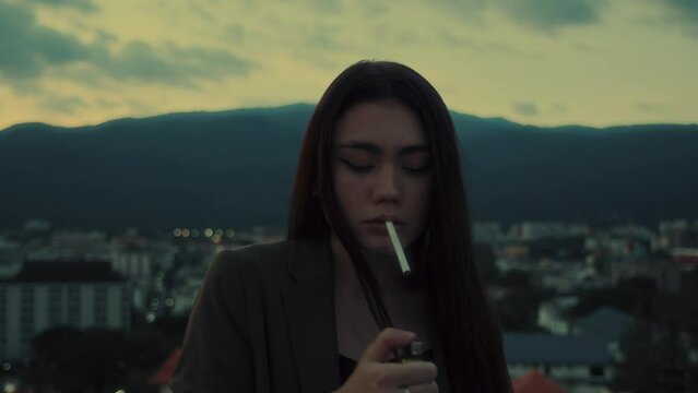 Young brunette woman smoking cigarette at rooftop with a mountain view