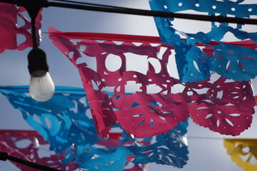 Mexican culture, colourful and shiny Papel Picado banners fluttering in the wind, light blue sky,...