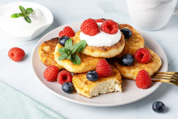 Cottage cheese pancakes with raspberries and blueberry on light background, breakfast or lunch