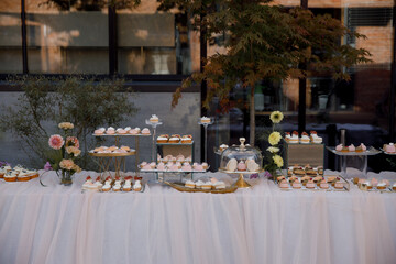 Luxury candy bar on golden wedding. Candy bar decorated by flowers standing of festive table with deserts, and cakes, strawberry tartlet, cupcakes and macarons. Wedding. Reception Tartlets