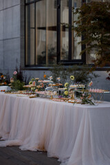 Candy bar. White wedding cake decorated with flowers standing table with deserts, strawberry tart and cupcakes. Wedding. Reception Tartlets