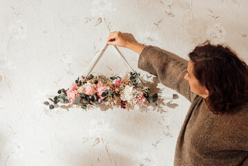 Mature woman standing and checking bouquet for hanging against wall