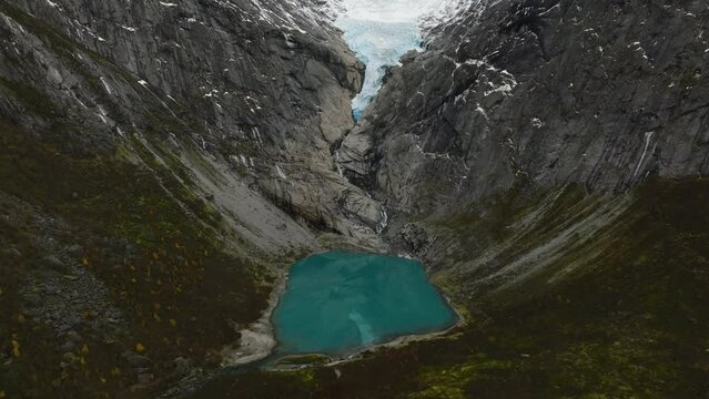 aerial view of briksdalsbreen glacier and blue glacial lake from high altitude in norway