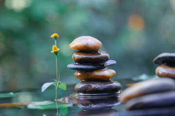 Stack of Balanced rocks pyramid on water with Golden light natural peace concepts bokeh on background