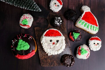 Homemade Glazed Christmas Donuts. Assorted Christmas design donuts include reindeer, Santa Claus, Xmas tree, and chocolate. festival background. copy space. festive or holiday concept.