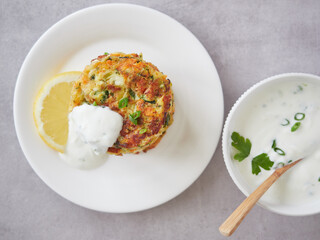 top view of crispy and appetizing vegetable pancakes on plate with yogurt and lemon sauce dressing....