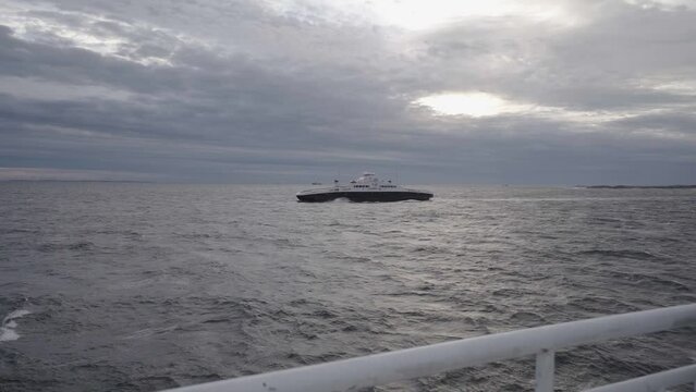 view on ferry in sea from other ferry in norway during cludy day in storm