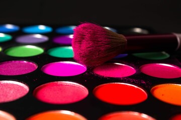 there are lots of color eyeshadow for makeup and one is a makeup brush - obrazy, fototapety, plakaty