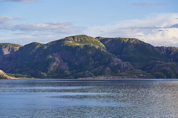 Landscape picture of the dramatic and wild coast of the Norwegian sea in the north Norway. Beautiful example of clean arctic style nature without people. Picture is taken in sunny summer evening.