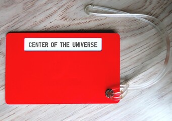 Red luggage tag with text label CENTER OF THE UNIVERSE, concept of people who thinks everything is about them, belief they are the center of everyone attention.