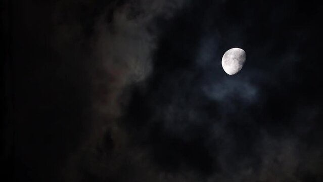 Moon on a dark cloudy night with clouds flying in front of the Moon like in thrillers and horror movies. Real shooting dark night sky, black clouds