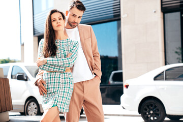 Beautiful fashion woman and her handsome elegant boyfriend in beige suit. Sexy brunette model in summer clothes. Fashionable smiling couple posing in street Europe. Brutal man and female outdoors