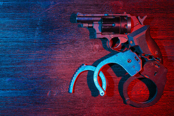 Police inspector handcuffs and revolver gun on the black table flat lay background with copy space....