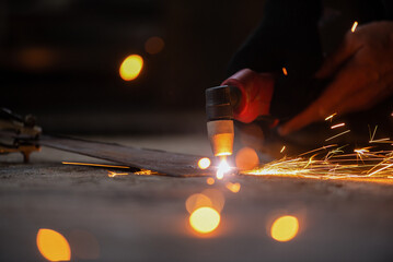 Welder cuts a metal sheet with a plasma cutter close up. - obrazy, fototapety, plakaty