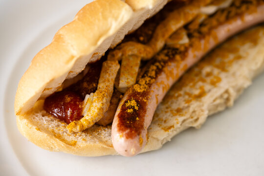 Bosna or Bosner Spicy Austrian Style Hot Dog with grilled Bratwurst, Onions, Tomato Ketchup and Curry in Selective Focus