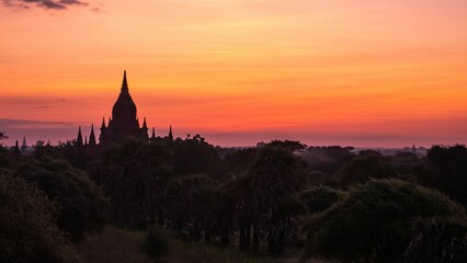 Buddhist temple silhouetted against a beautiful sunset sky over a rural area in Myanmar